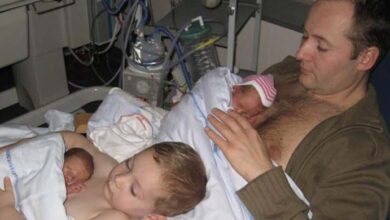 Photo of Young boy helps dad to keep his newborn twin siblings warm in viral photo